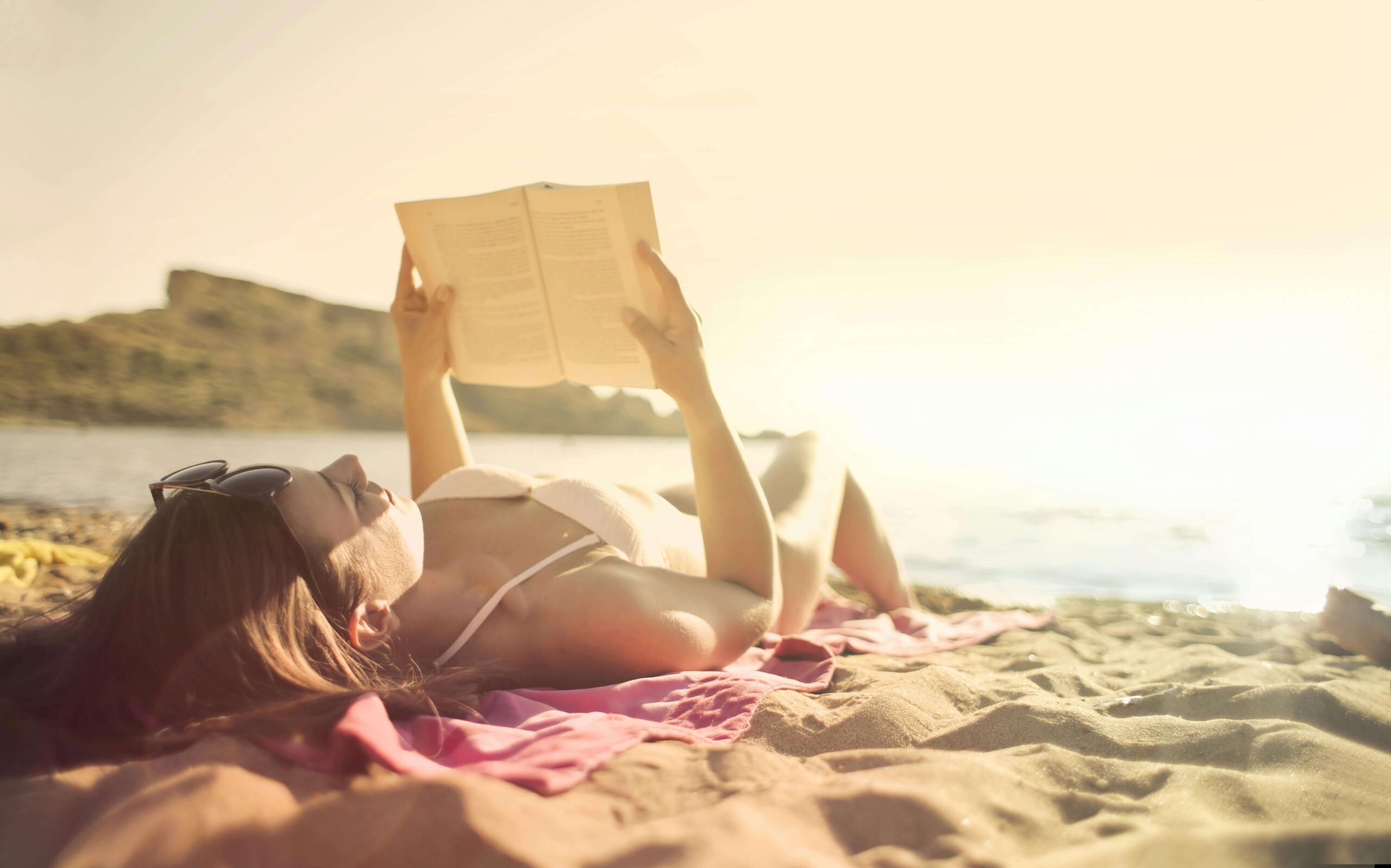 Woman enjoying reading a book while lying at the beach