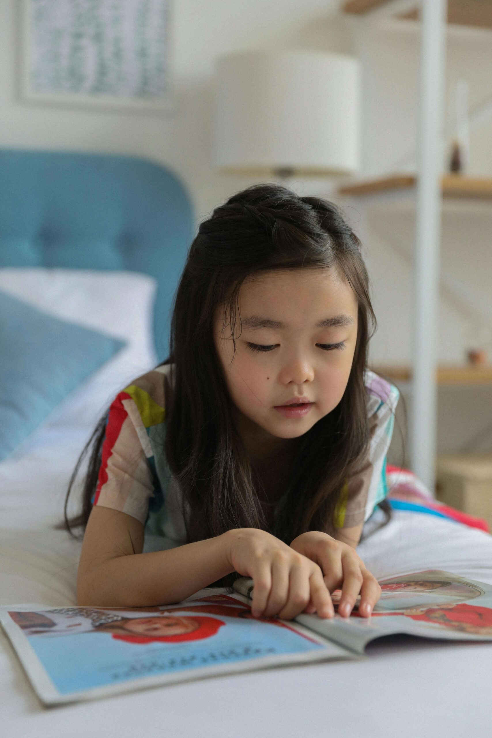 girl reading a children's book on her bed