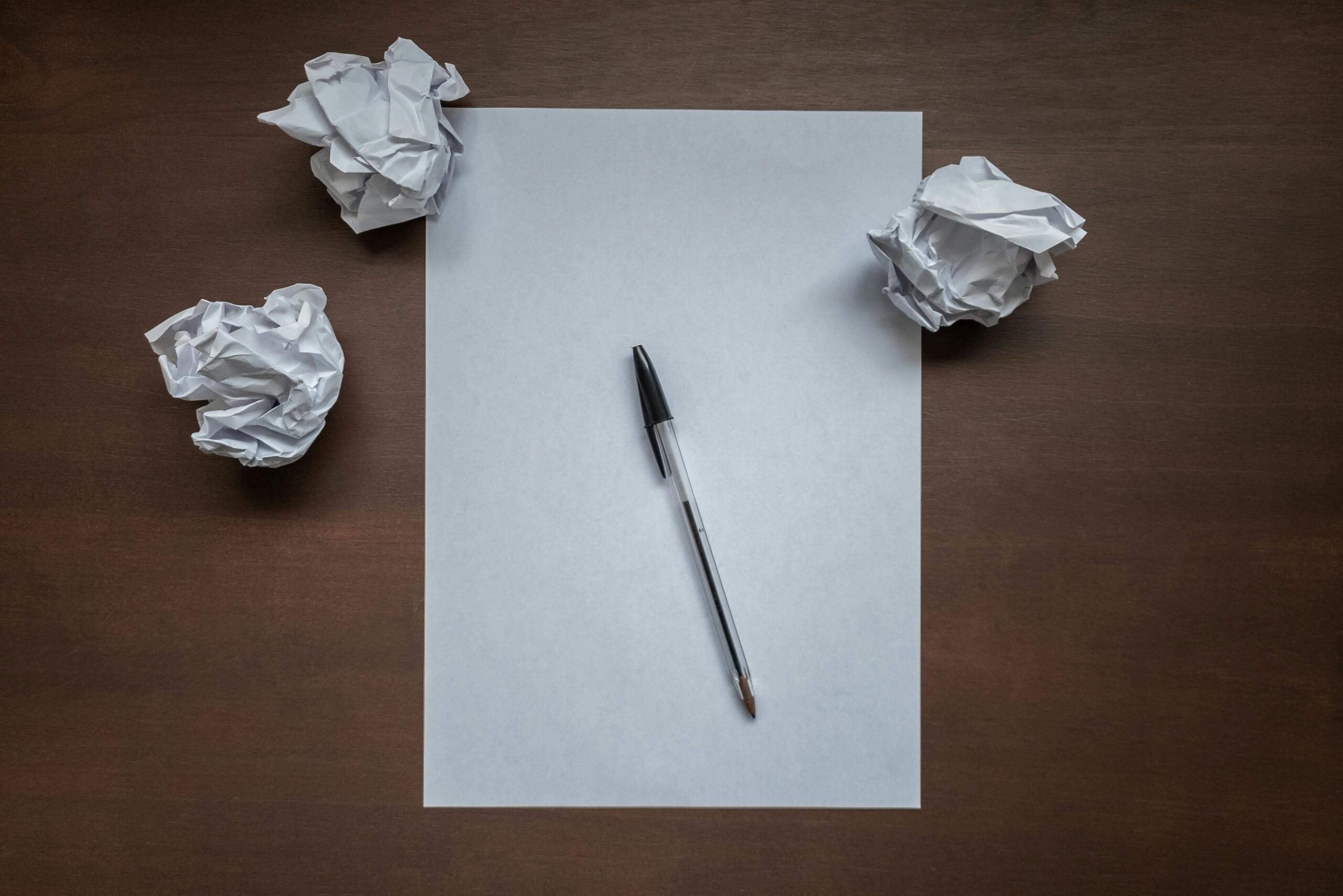 Crumpled paper, a plain paper pad, and a pen