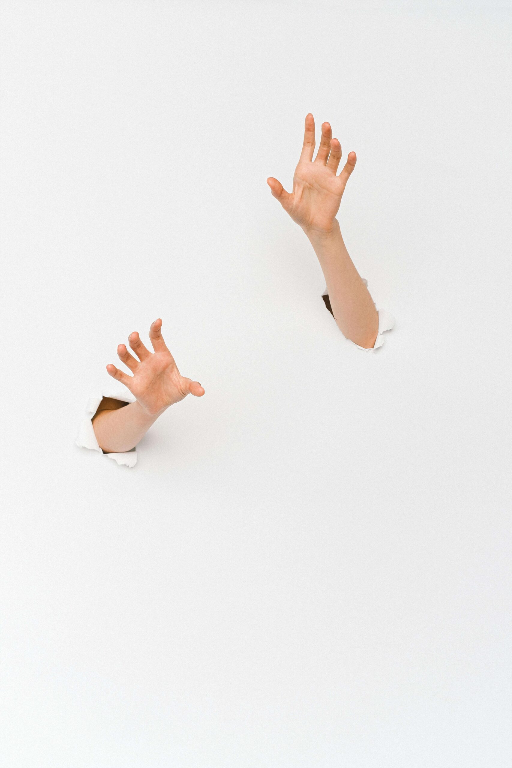 hands breaking through white wall