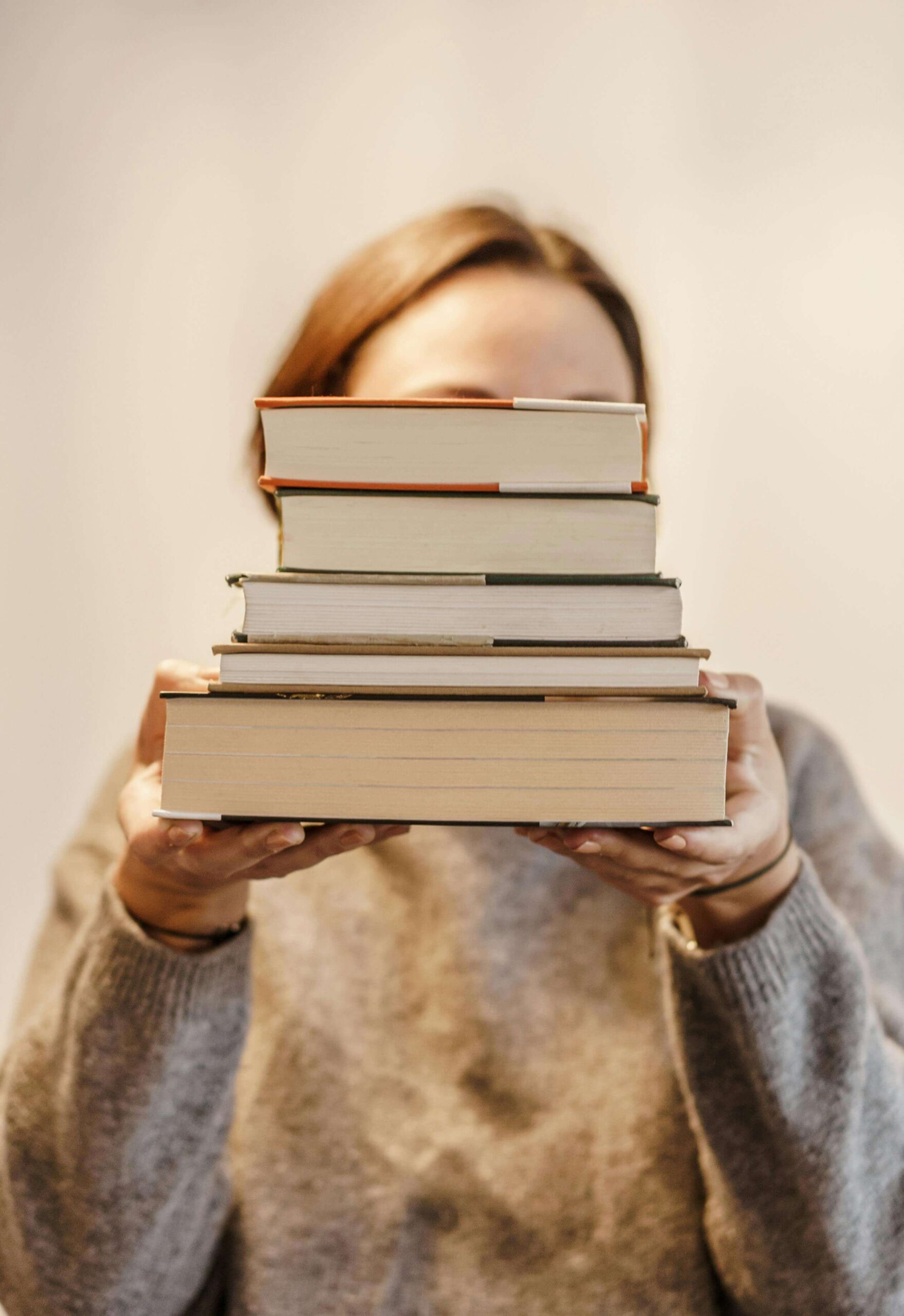 woman holding up a stack of hard-cover books