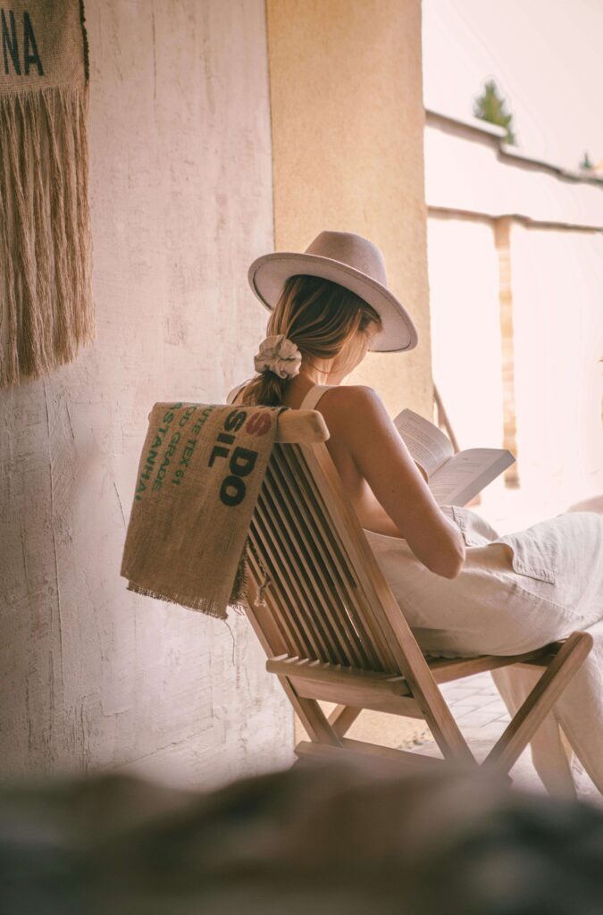 young lady reading a book while sitting on a chair