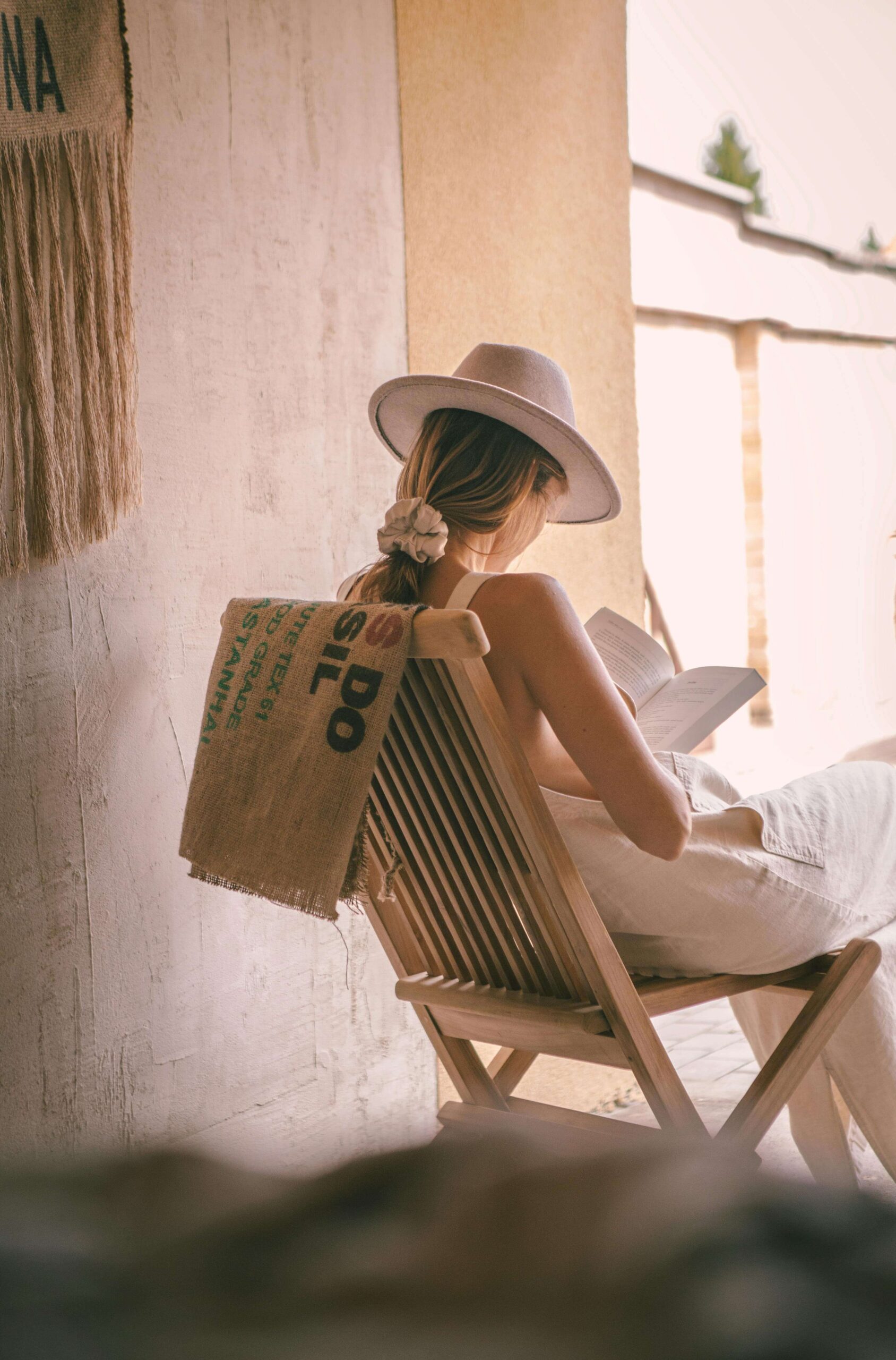 young lady reading a book while sitting on a chair