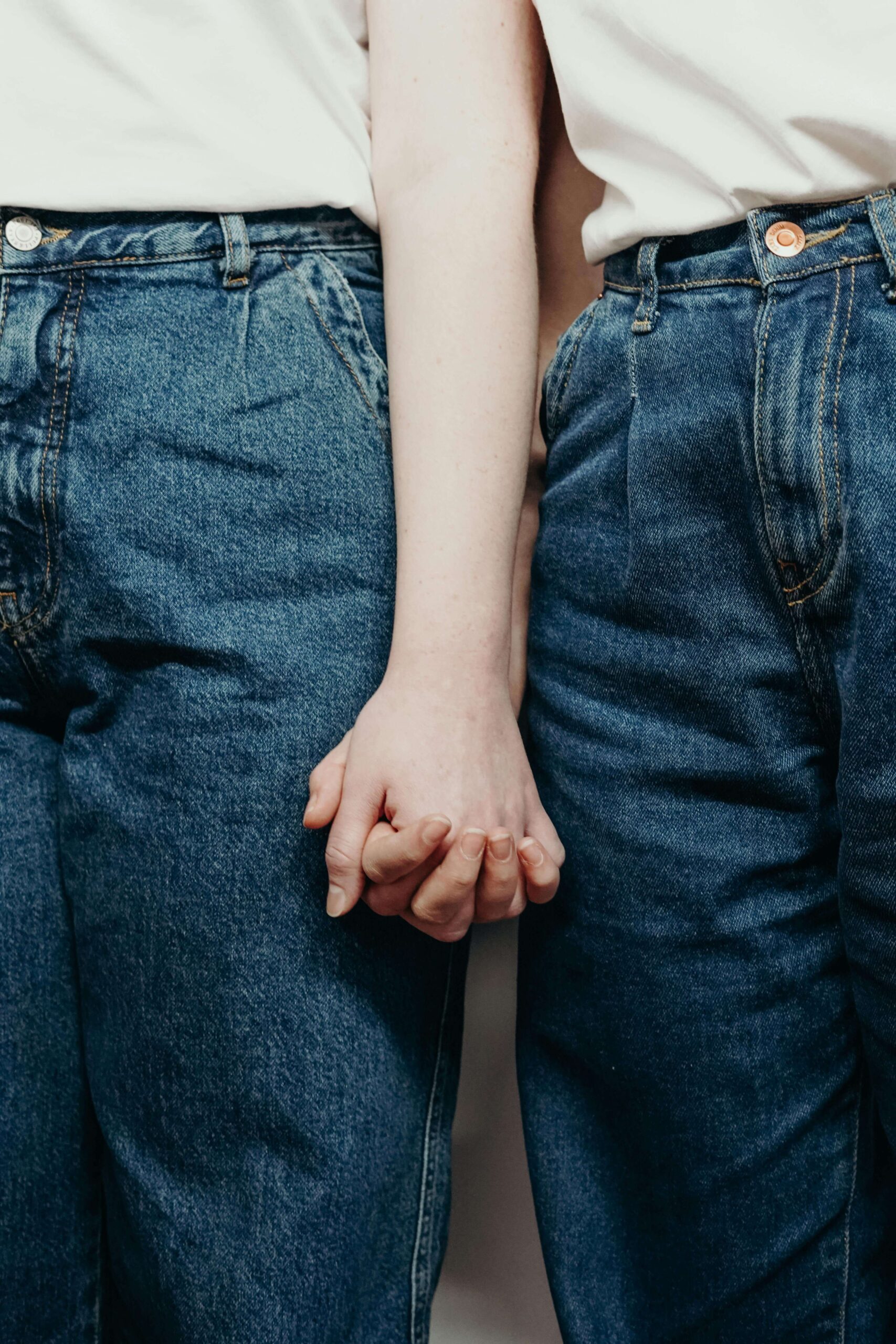 two females in jeans holding hands