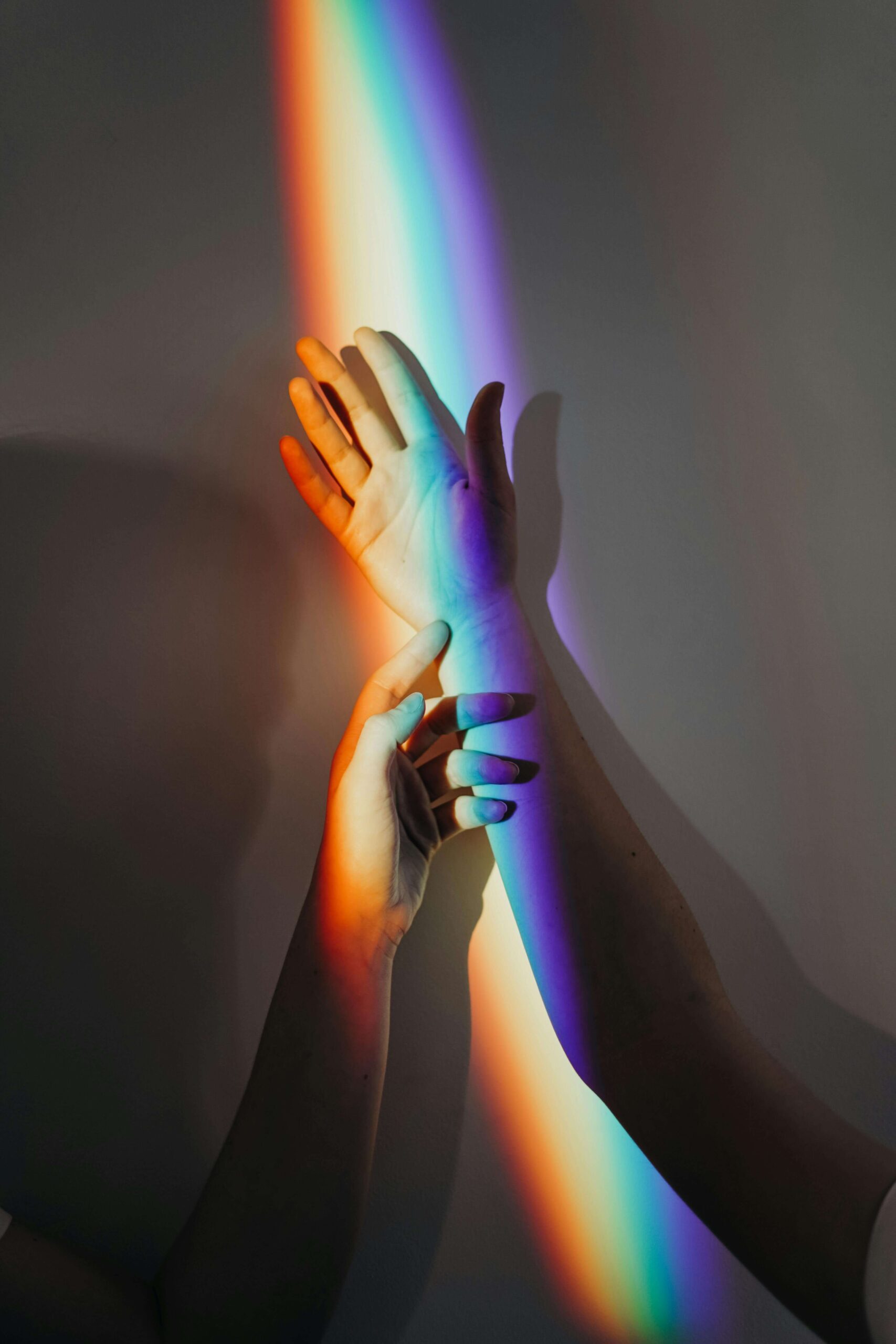 two hands reflecting the spectrum color rainbow symbolizing the lgbtq